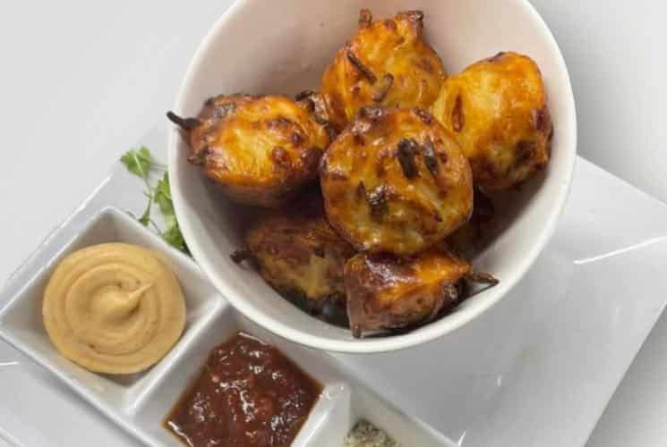 Close up view of potato muffins in white bowl with multiple dipping sauces