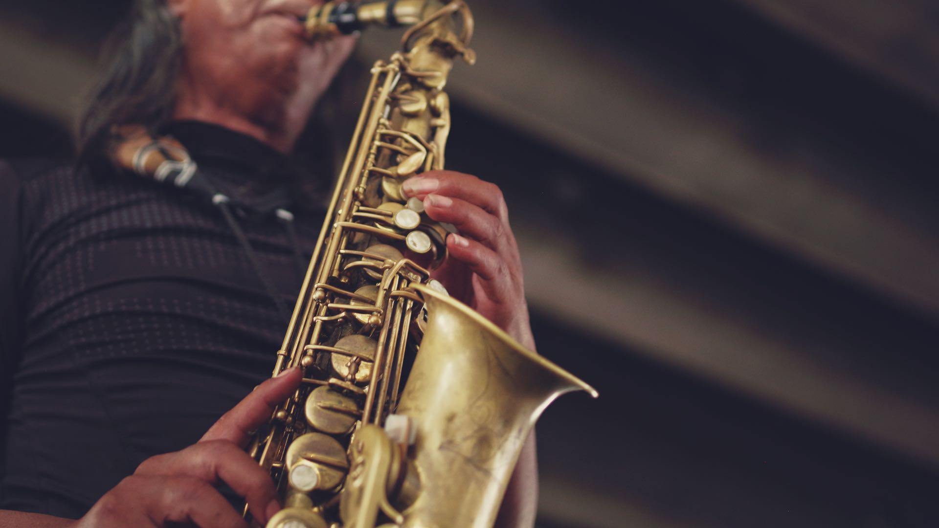 Close up view of man in black shirt playing a saxophone