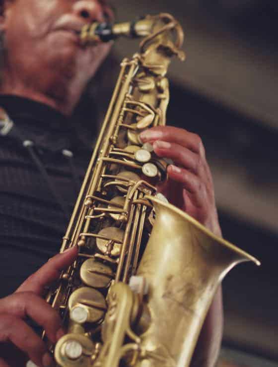 Close up view of man in black shirt playing a saxophone